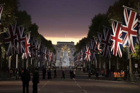 People assemble on the Mall in front of Buckingham Palace ahead of the Queen's funeral. After the service, the sovereign's flag-draped coffin will travel by hearse down the Mall to her final resting place in St. George's Chapel, within the grounds of Windsor Castle.