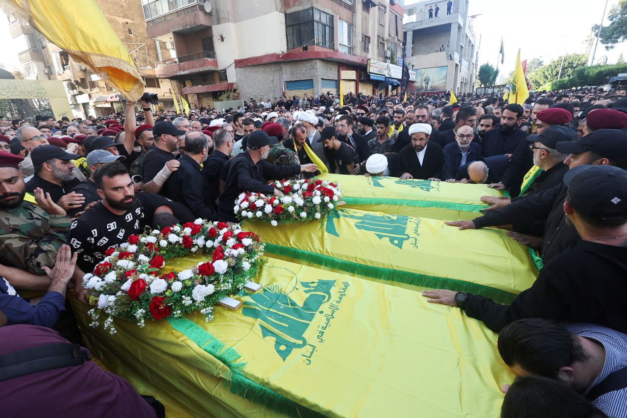 People stand next to coffins during a funeral for three Hezbollah members who were killed by an Israeli strike in Beirut, Lebanon, on September 21. 