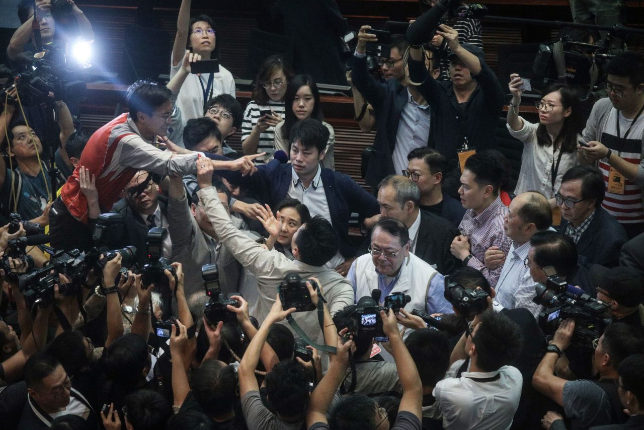 Hong Kong pro-Beijing lawmaker Abraham Shek (centre right in white vest) is escorted from a legislative meeting after scuffles broke out between pro-Beijing and pro-democracy lawmakers over the proposed extradition law in the Legislative Council in Hong Kong on May 11, 2019. 