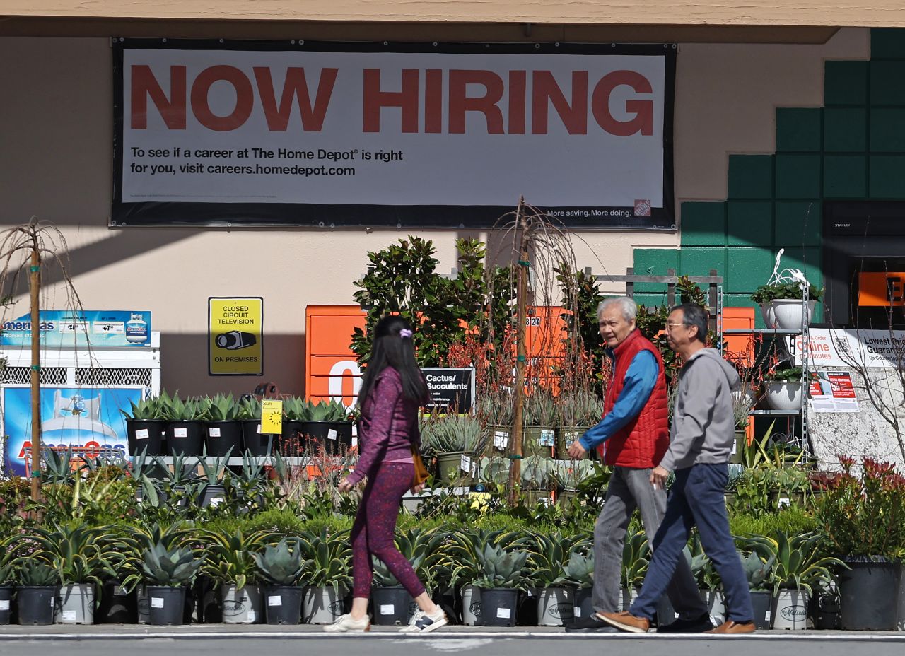 People walk by a “now hiring” sign at a Home Depot store in San Rafael, California, on March 8.