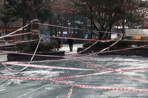 A woman wearing a face mask walks near a park, which is taped off to comply with social distancing measures in Seoul, South Korea on January 14.