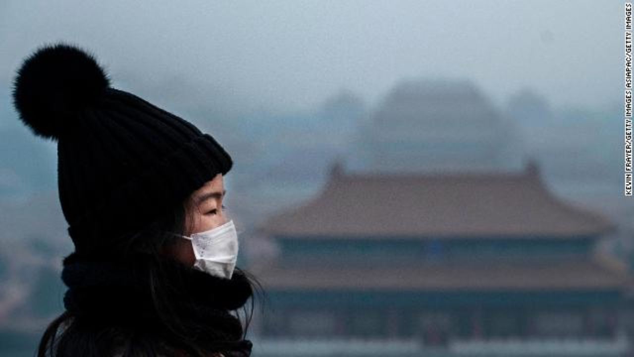 A Chinese girl wears a protective mask as she stands looking towards the Forbidden City, which was closed by authorities, in Beijing. 