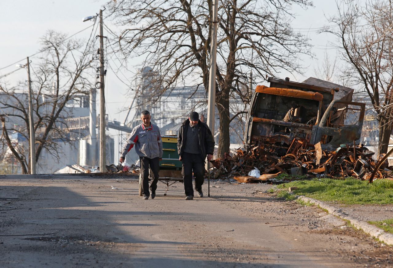 Local residents walk past a destroyed vehicle in the southern port city of?Mariupol, Ukraine, on April 20.
