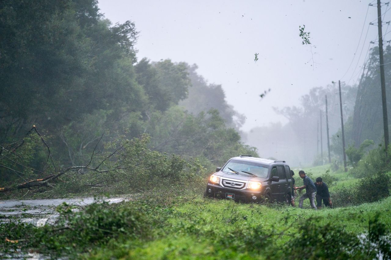 People work to free a vehicle stuck on the shoulder of a road near Mayo.