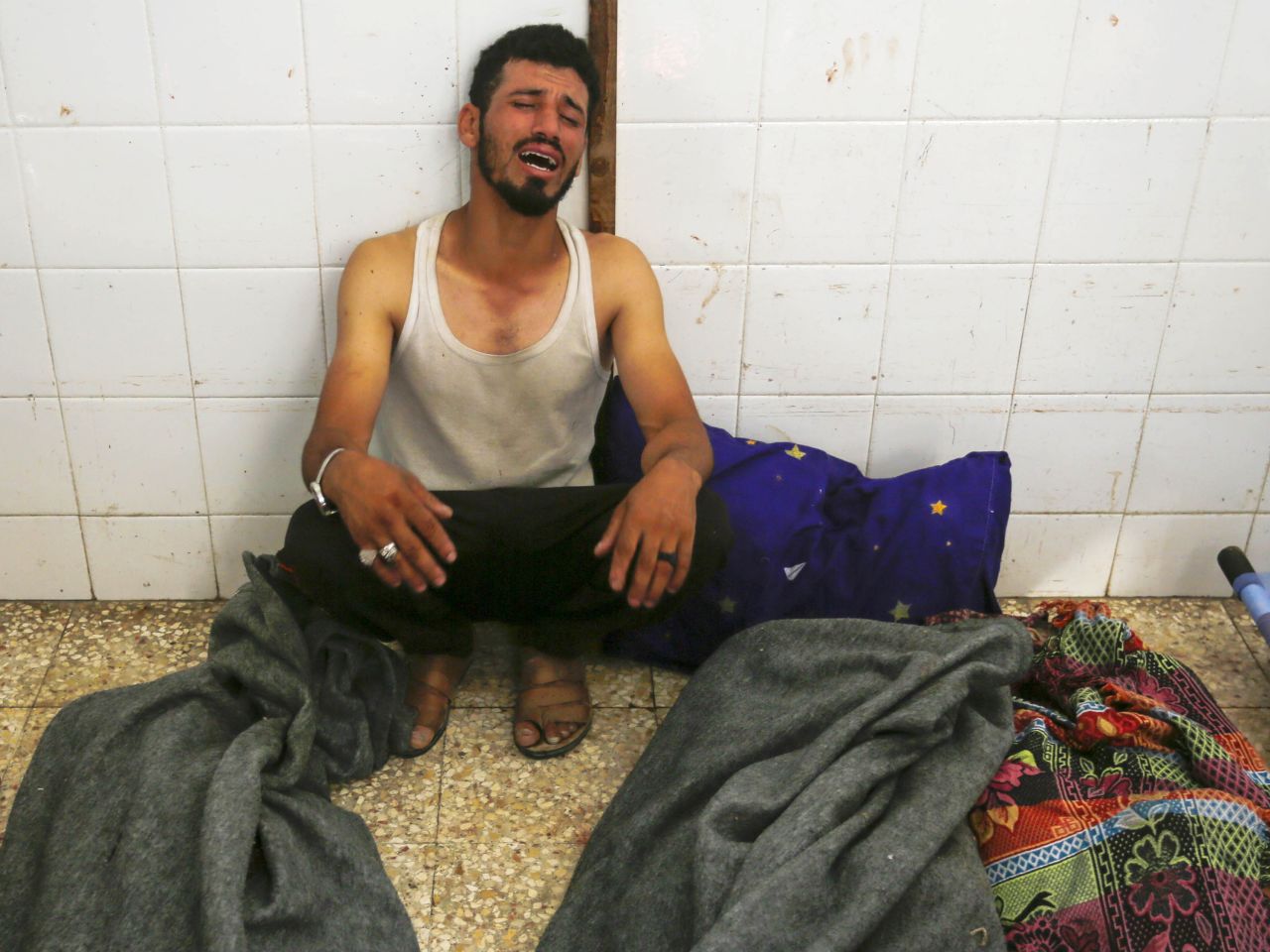 A man sits next to the covered bodies of Palestinians at the Al-Aqsa Martyrs Hospital morgue in Deir al-Balah, Gaza on June 8.