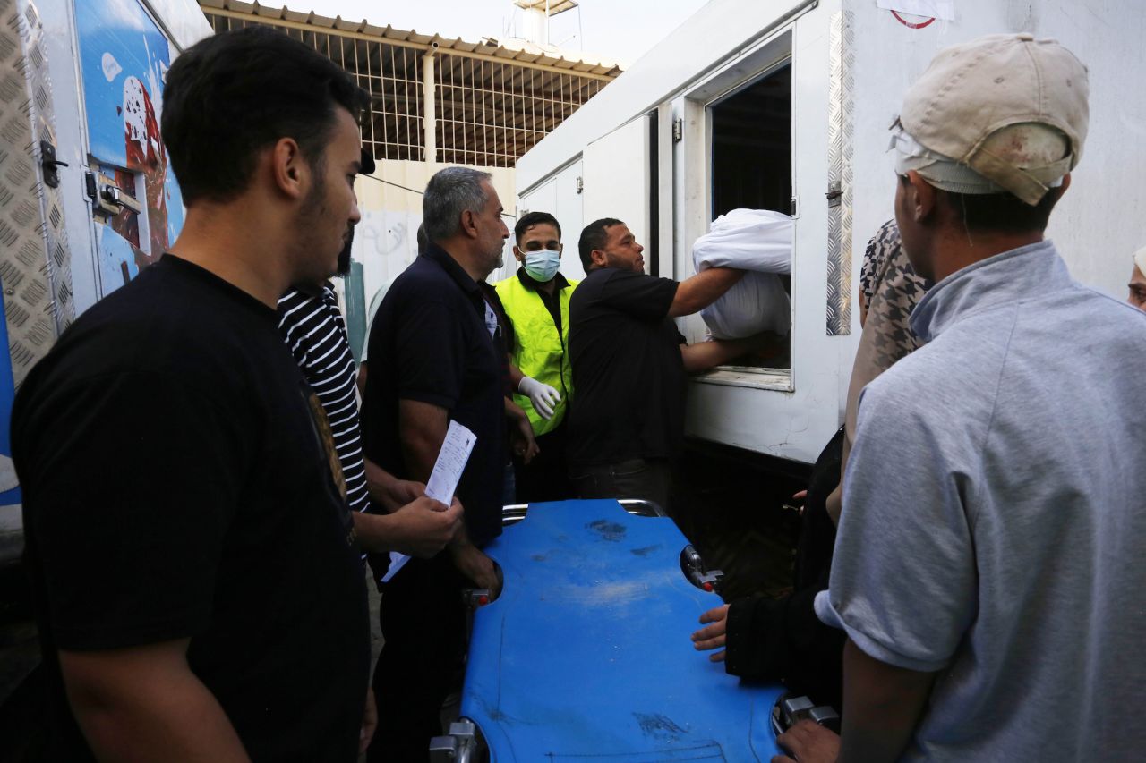 A man carries a dead body to an ice cream refrigerator due to the insufficiency of hospital morgues in Deir al-Balah, Gaza, on October 14.