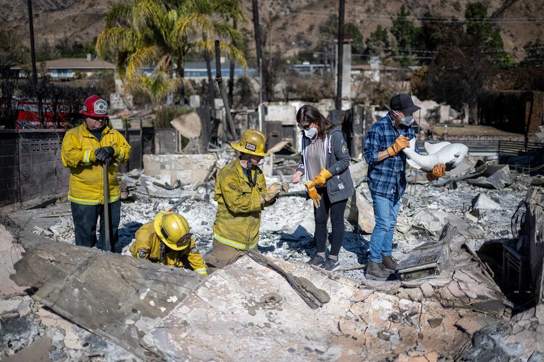 El capitán de Cal Fire Jeff Crile, el ingeniero Michael Gonzales y el bombero Trent Houser ayudan a Darryl y Christine Montes a buscar algo de valor entre los escombros de su casa en Pasadena el jueves.