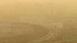 Vistos a través de una ventana de vidrio, los autos circulan por una autopista durante una tormenta de polvo en medio de una fuerte contaminación en Pekín, el 10 de marzo de 2023.