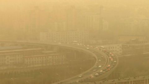 Vistos a través de una ventana de vidrio, los autos circulan por una autopista durante una tormenta de polvo en medio de una fuerte contaminación en Pekín, el 10 de marzo de 2023.
