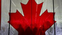 Los partidarios proyectan sombras sobre una bandera canadiense mientras se reúnen antes de un evento de campaña electoral para el líder del Partido Conservador de Canadá, Pierre Poilievre, en Vaughan, Ontario, el 22 de abril.