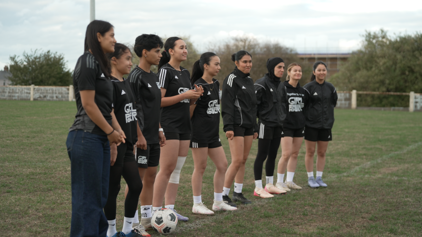 Afghan women's soccer players in exile hold hands on a training pitch in Doncaster, England with former coach and mentor Khalida Popal.