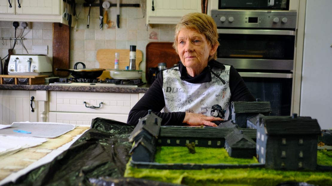 Local historian Catherine Corless sits with the clay model she made of the Tuam institution in her kitchen in rural County Galway. Corless said the start of the excavation has provided a sense of “relief.”