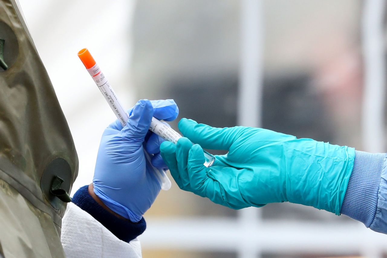 Medical professionals pass each other a coronavirus test at a drive-thru testing site at Cambridge Health Alliance Somerville Hospital on April 28 in Somerville, Massachusetts. 