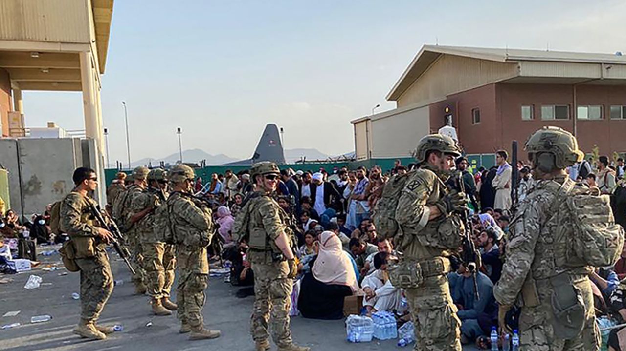 US soldiers stand guard as Afghans wait to board a US military aircraft to leave Afghanistan, at the military airport in Kabul on August 19,  after Taliban's military takeover of Afghanistan.