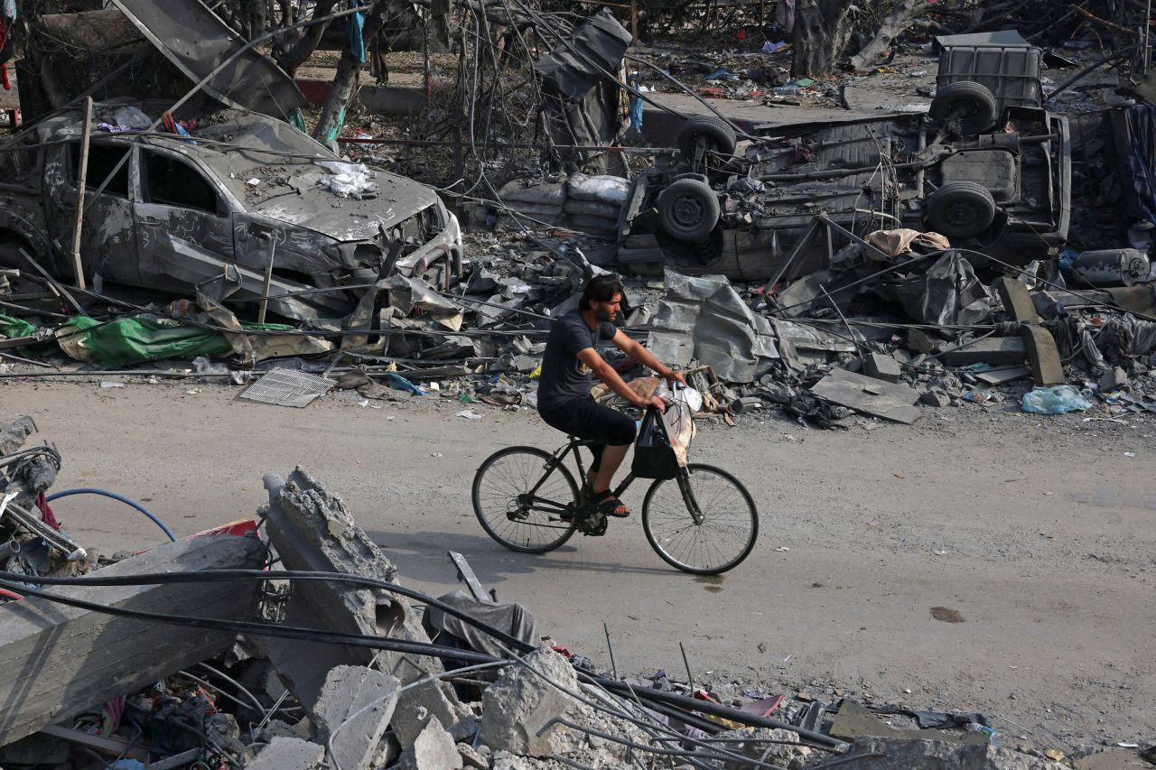  A youth rides a bicycle past wrecked cars in the aftermath of Israeli bombing in Rafah, Gaza, on October 28.