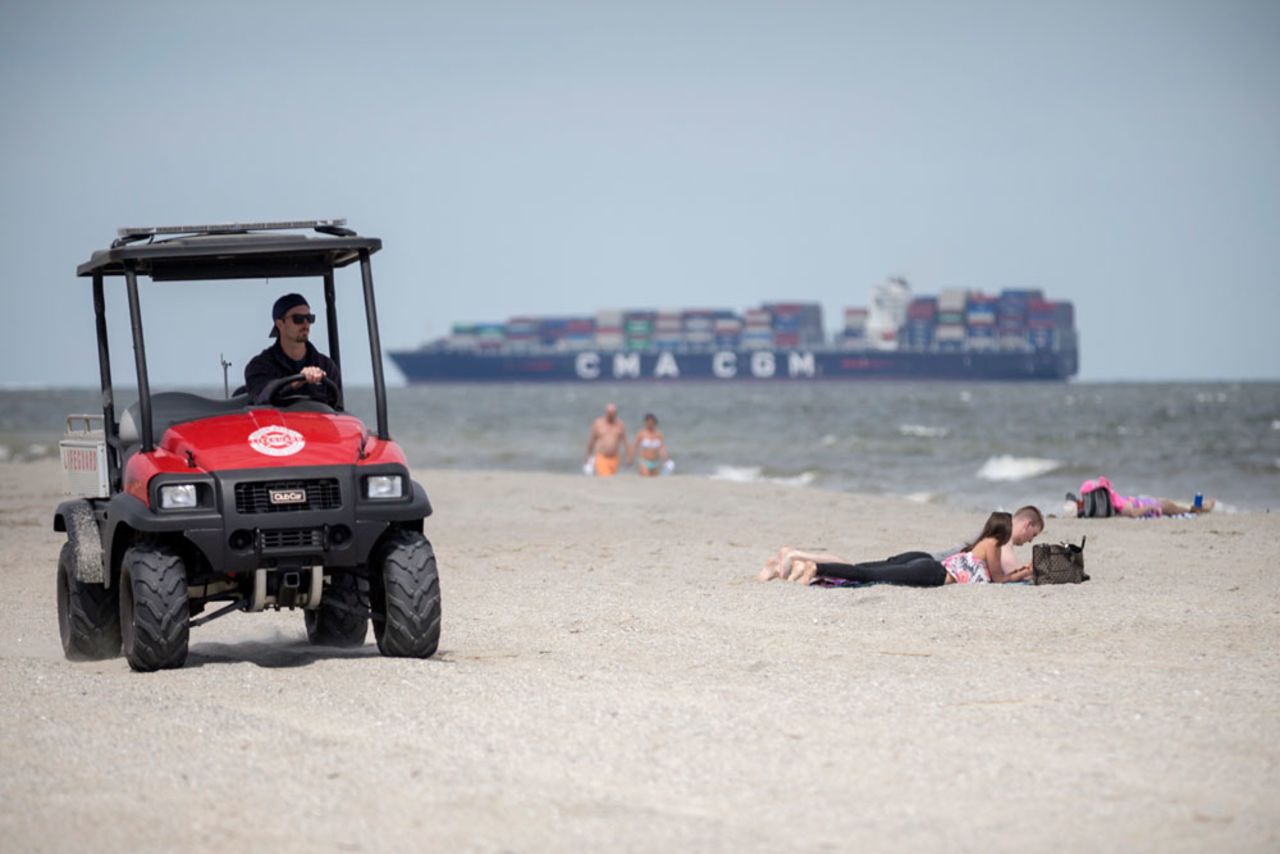 A member of the Tybee Island, Georgia, Life Guards, left, patrols the beach on an ATV while visitors sunbathe on the sand on April 4 after Gov. Brian Kemp signed an executive order allowing people to exercise outside, with social distancing of at least six feet because of the coronavirus outbreak. 