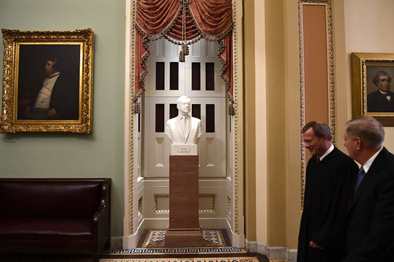 US Supreme Court Chief Justice John Roberts, left, and Senator Lindsey Graham walk past a bust of former US President Richard Nixon after the Senate impeachment vote.