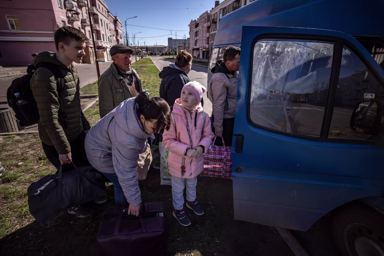 People wait for a bus as a children looks at the sky, a day after a rocket attack at a train station, in Kramatorsk, Ukraine on April 9.