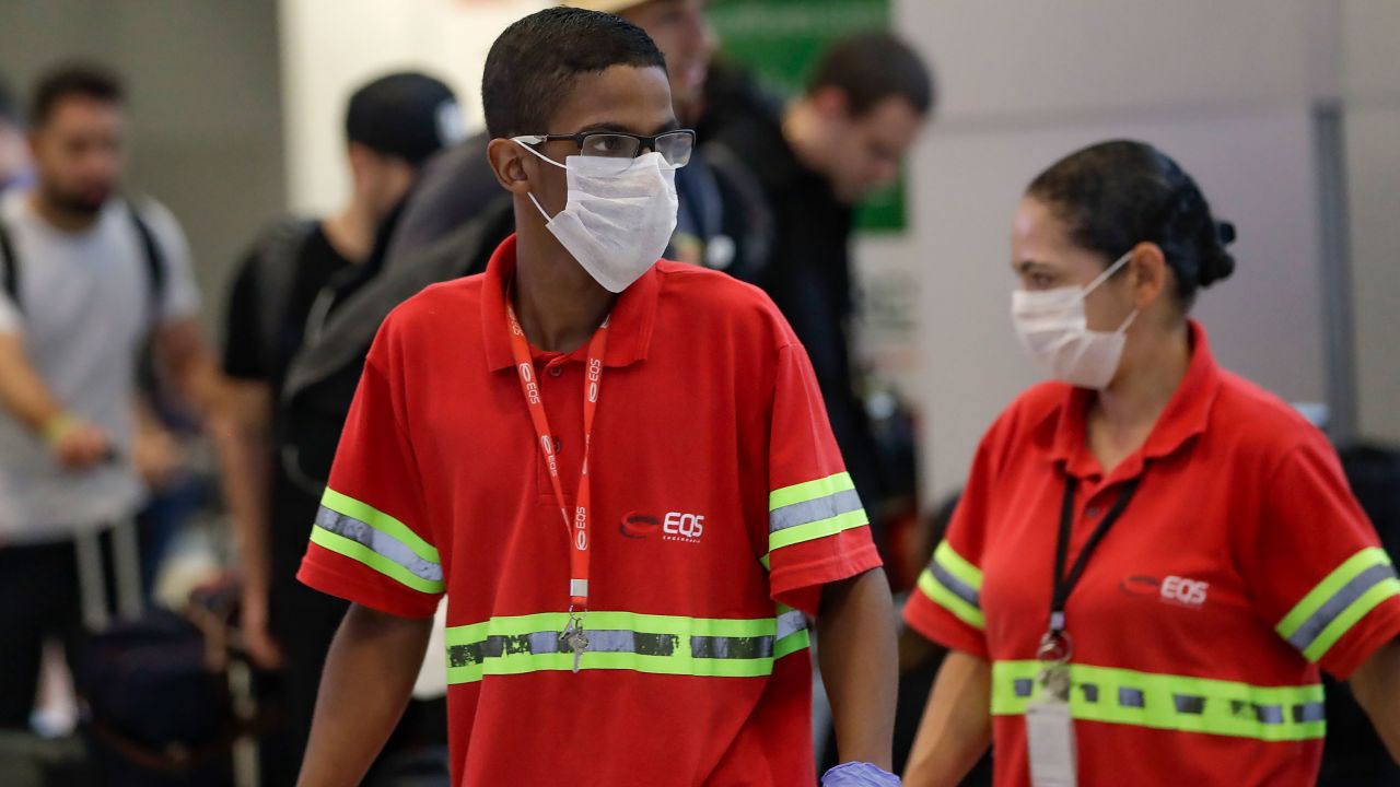 Airport employees wear masks as they work at the Sao Paulo International Airport in Sao Paulo, Brazil, on Wednesday, February 26.