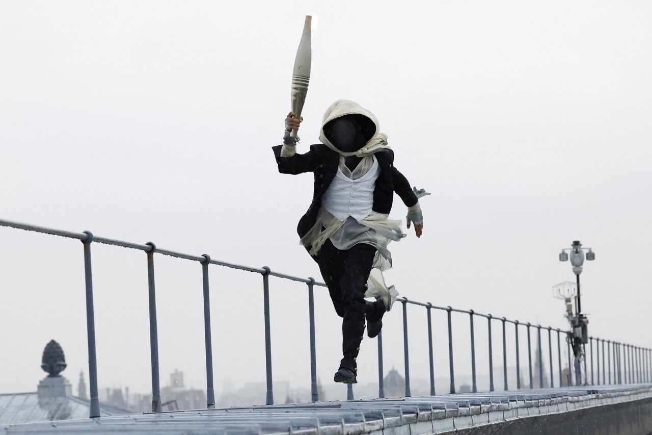 A torch bearer runs atop the Musee d'Orsay today in Paris during the opening ceremony.