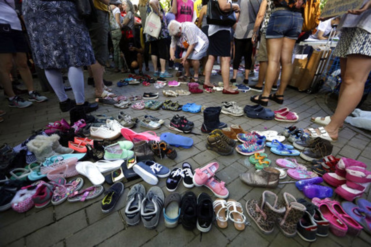 Children's shoes are used in a protest by thousands as they crowd Rittenhouse Square near a hotel hosting a meeting with Vice President Mike Pence, Tuesday June 19, 2018 in Philadelphia. The children's shoes reference the current practice of separating children from parents accused of crossing the border illegally. 