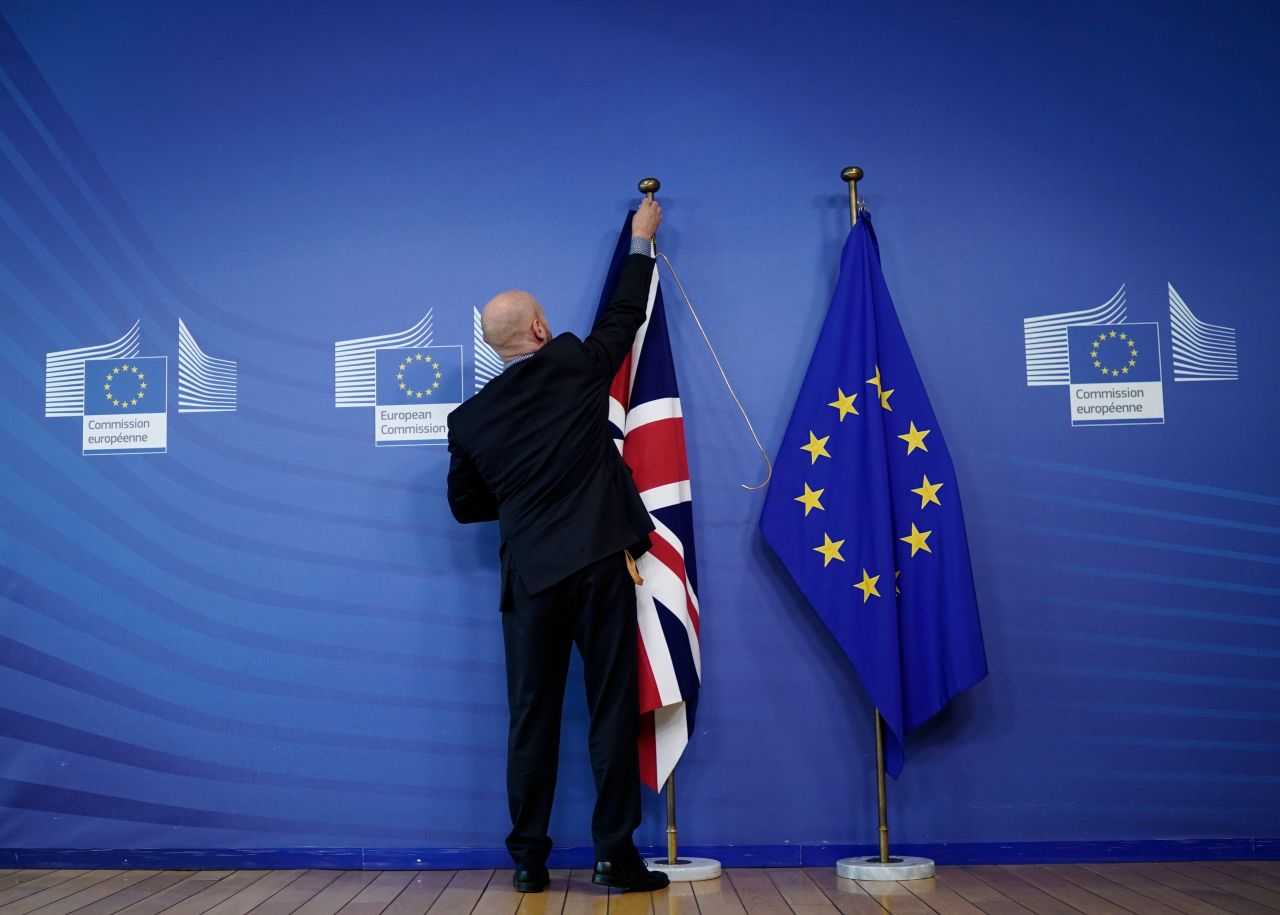 An official hangs a Union Jack next to an European Union flag at EU Headquarters in Brussels.