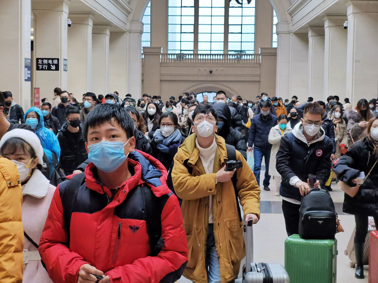 People wear face masks as they wait at Hankou Railway Station on Wednesday in Wuhan, China.