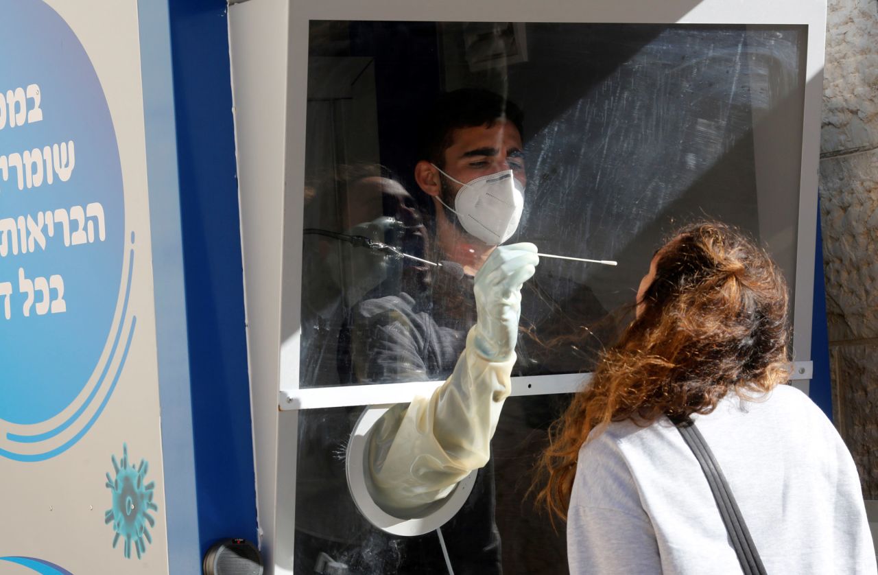 A medical worker collects a swab from a woman for a COVID-19 test at Maccabi Healthcare Services Center in Modiin, Israel, on December 27.