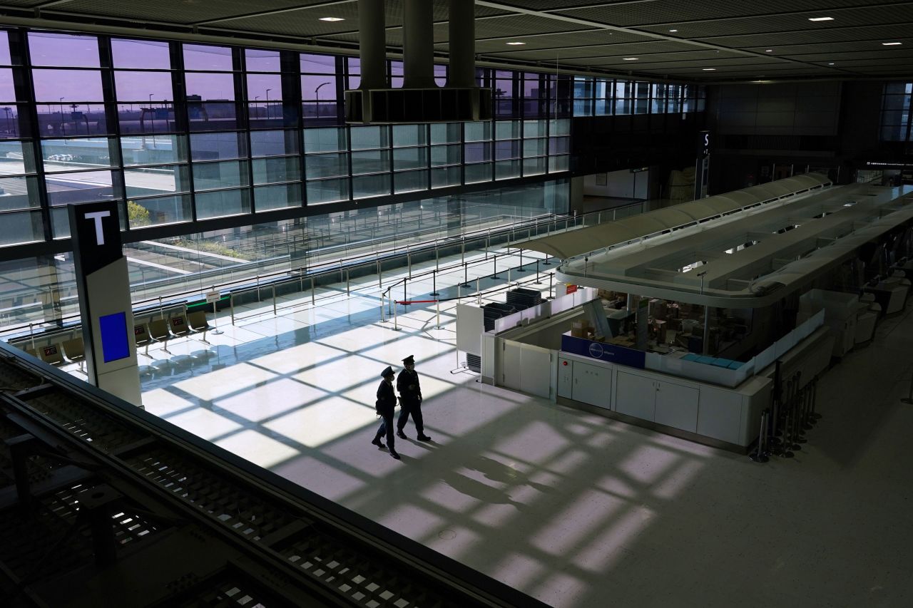 Police officers patrol an empty check-in area in a departure hall at Narita Airport in Japan on November 30.