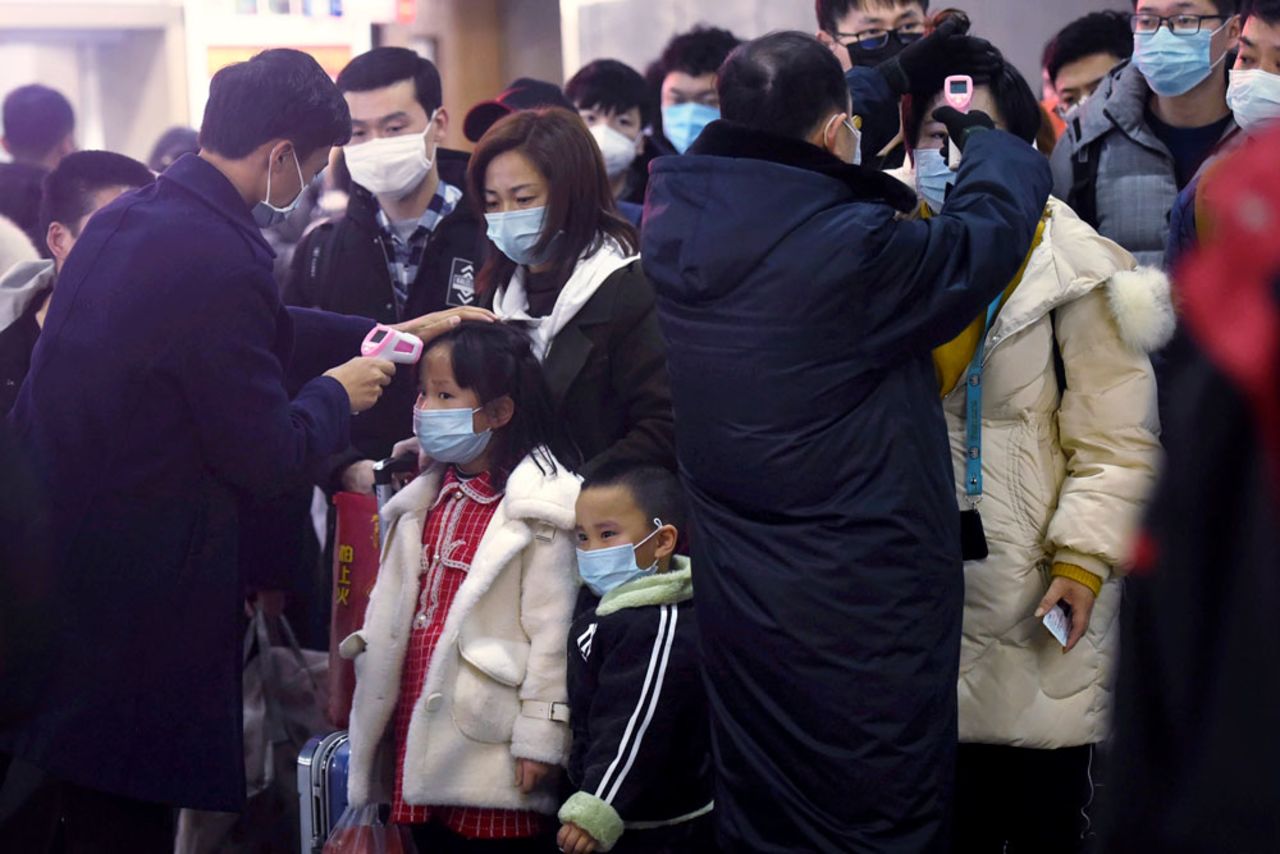 Workers use infrared thermometers to check the temperature of passengers arriving from Wuhan at a train station in Hangzhou on Thursday, January 23.