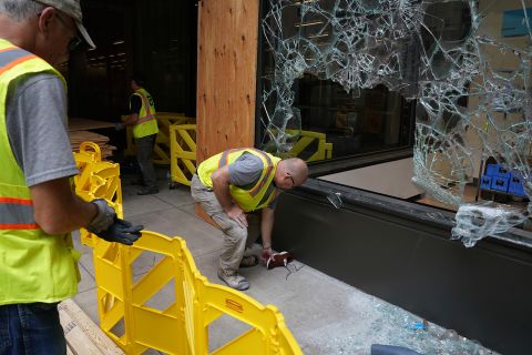 A worker picks up a shoe outside one of the broken windows at the Nordstrom Rack on Nicollet Mall, Thursday, Aug. 27, in Minneapolis.