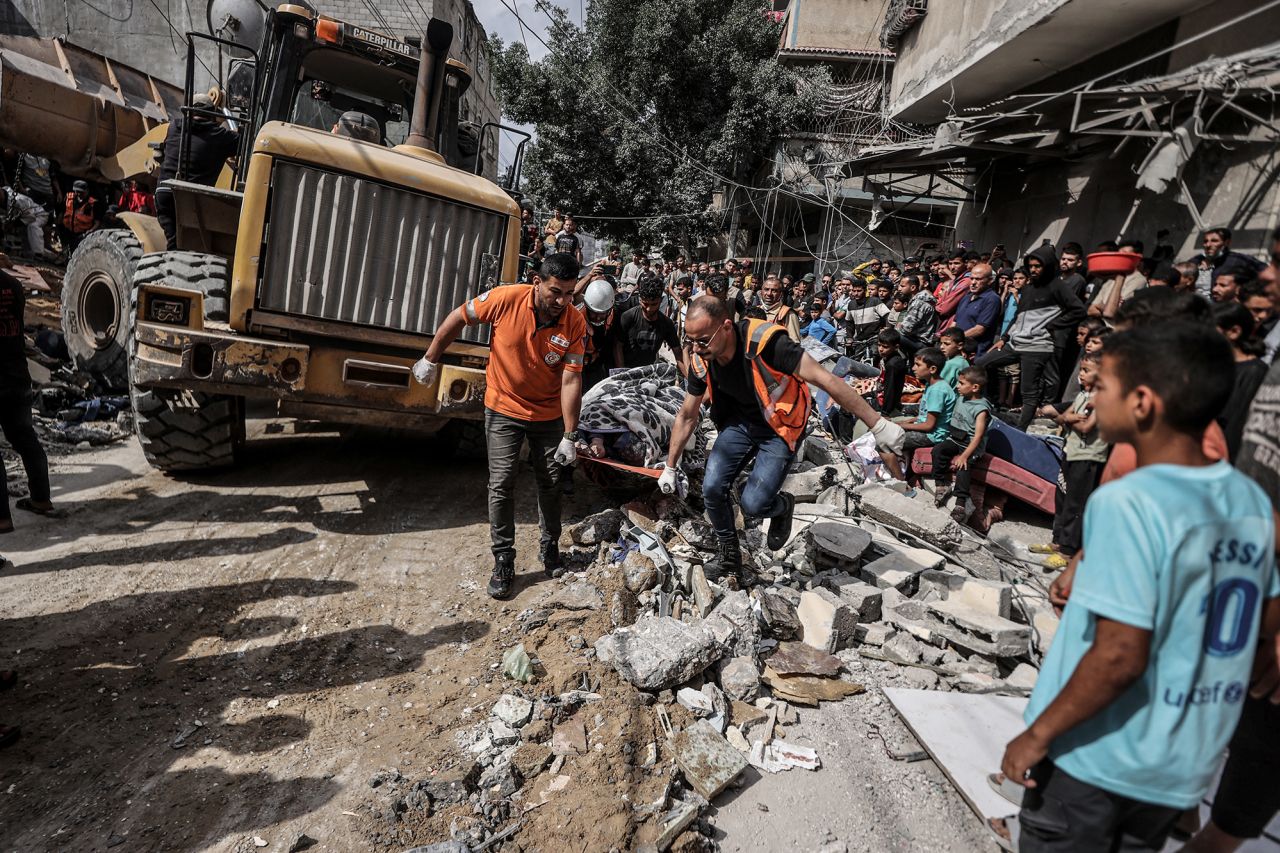 A body is pulled out from under the rubble of a collapsed building as a civil defense team and residents carry out a search and rescue operation at the Nuseirat Refugee Camp in Deir al-Balah, Gaza, on May 14.