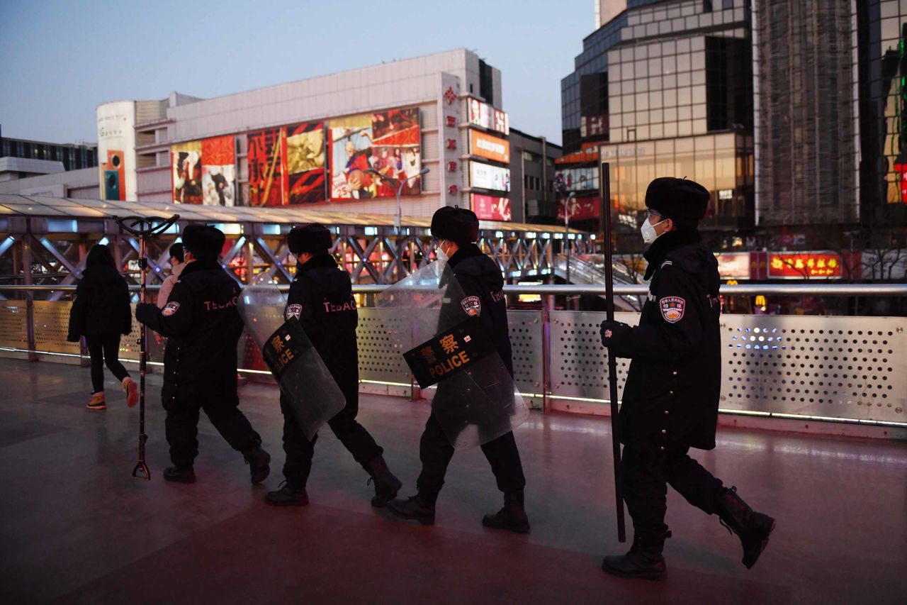 Security guards wearing protective masks patrol a shopping area in Beijing on Monday.