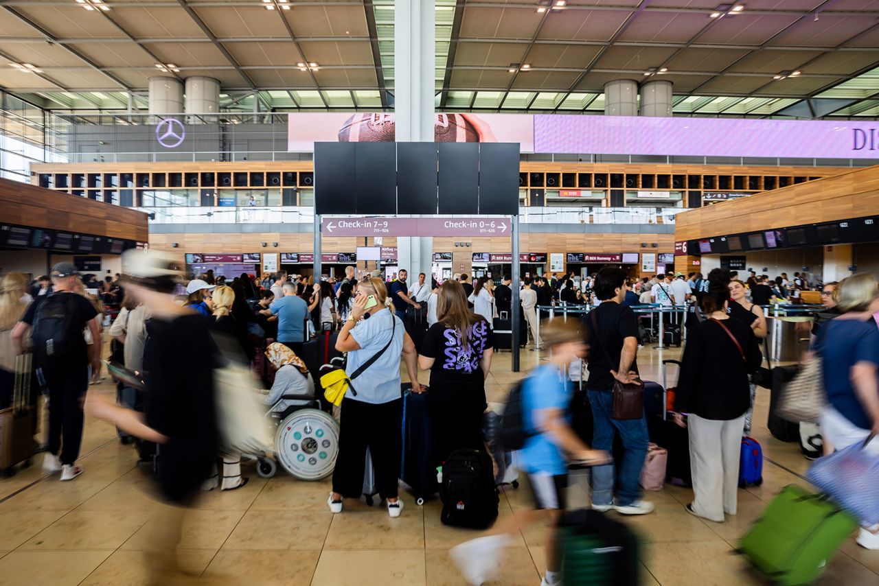 Numerous passengers wait in front of a black display board at the capital's Berlin Brandenburg Airport, in Schönefeld, Germany, on July 19.
