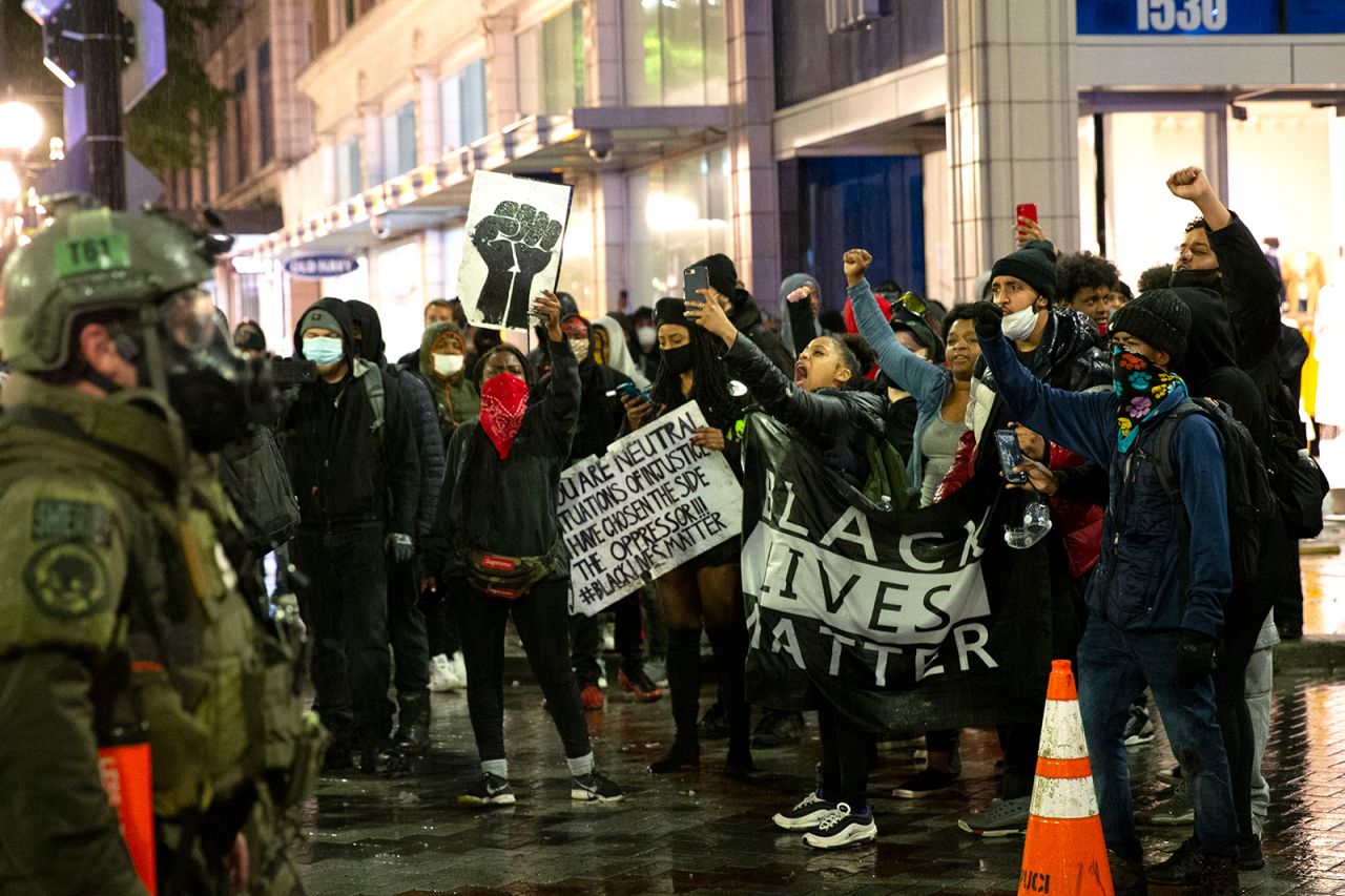 Protesters holding a Black Lives Matter banner shout at law enforcement officers on May 30, in Seattle, Washington. 