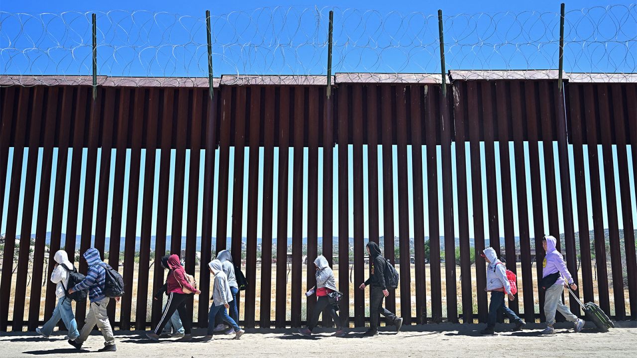 Migrants walk on the US side of the border wall in Jacumba Hot Springs, California, on June 5, after crossing from Mexico. 