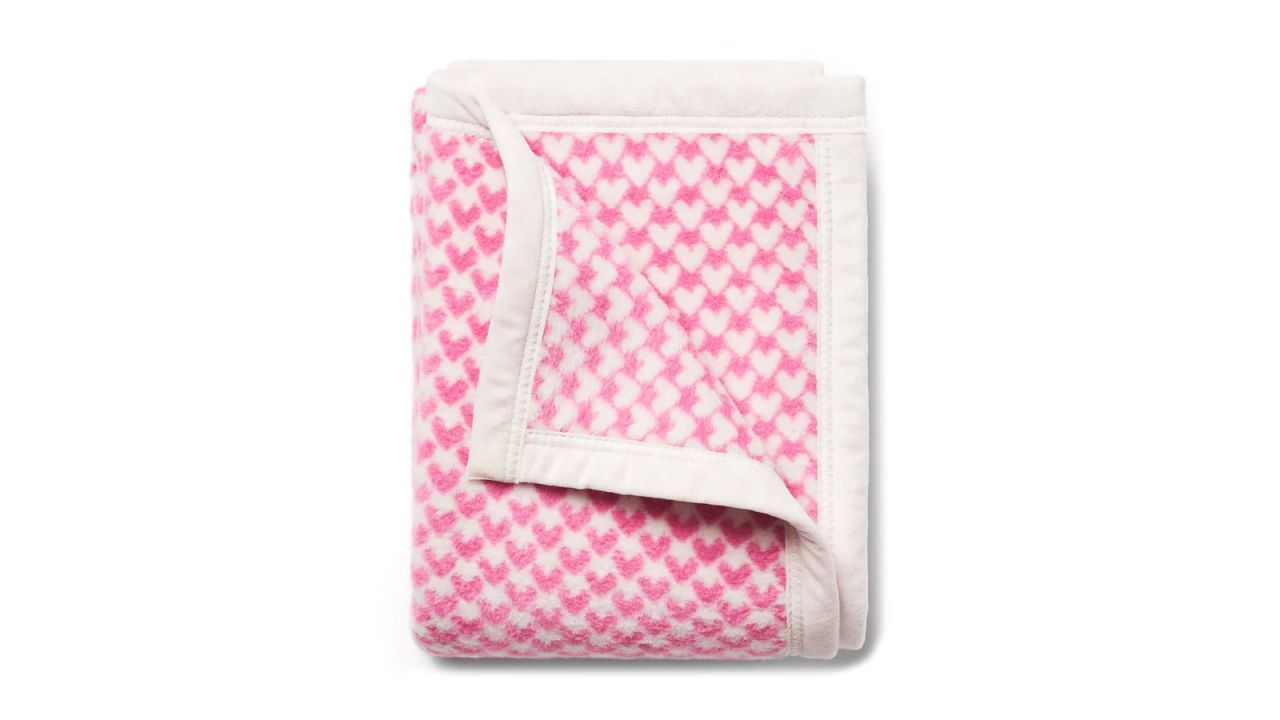 A folded blanket with pink and white hearts.