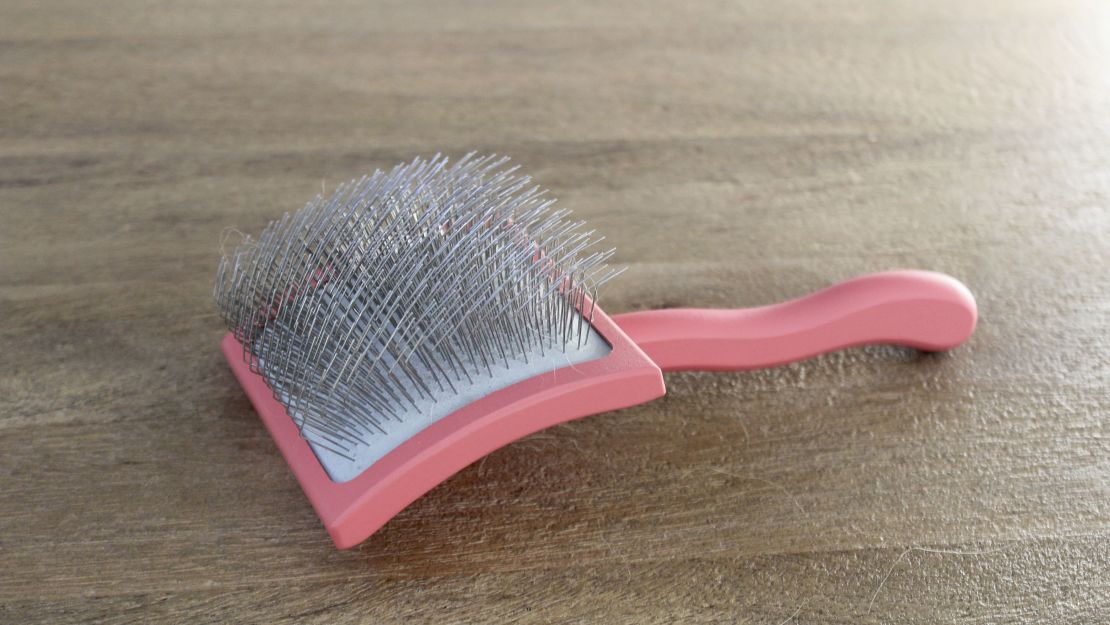 A red slicker brush on a wooden surface.