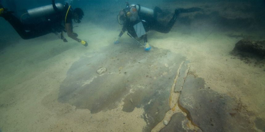 Members of the dive team move away sand from a polished floor that was part of the port.