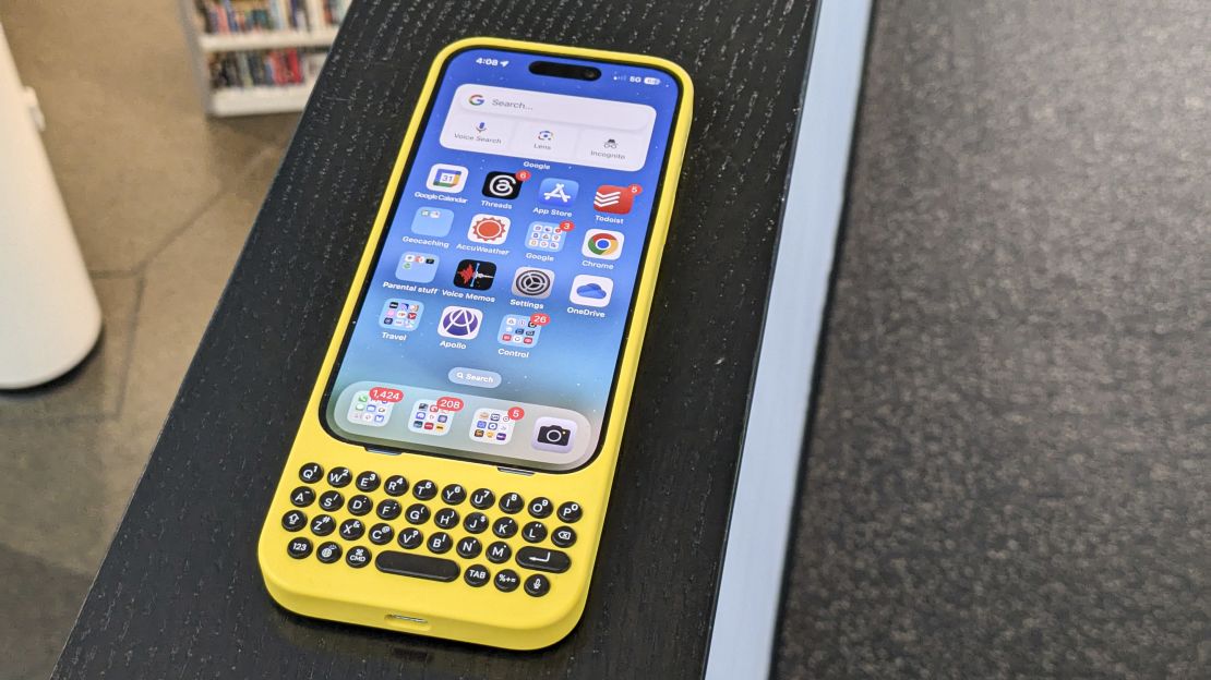 Yellow Clicks keyboard case with iPhone 15 Pro attached on a table.