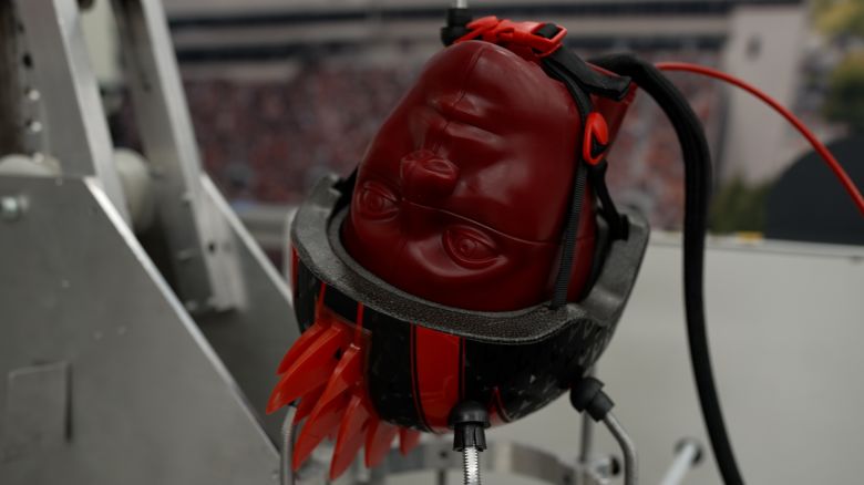A youth bicycle helmet-clad test headform with sensors inside is prepped for an impact test in the Virginia Tech Helmet Lab.