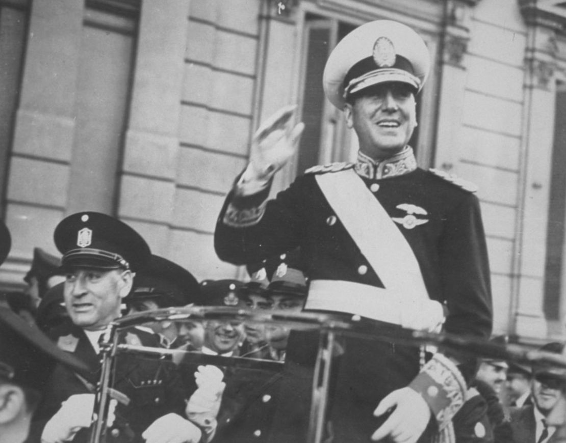 Juan Domingo Perón, sonriendo desde el automóvil oficial mientras recorre la Avenida de Mayo hacia la Casa de Gobierno para asumir la presidencia.