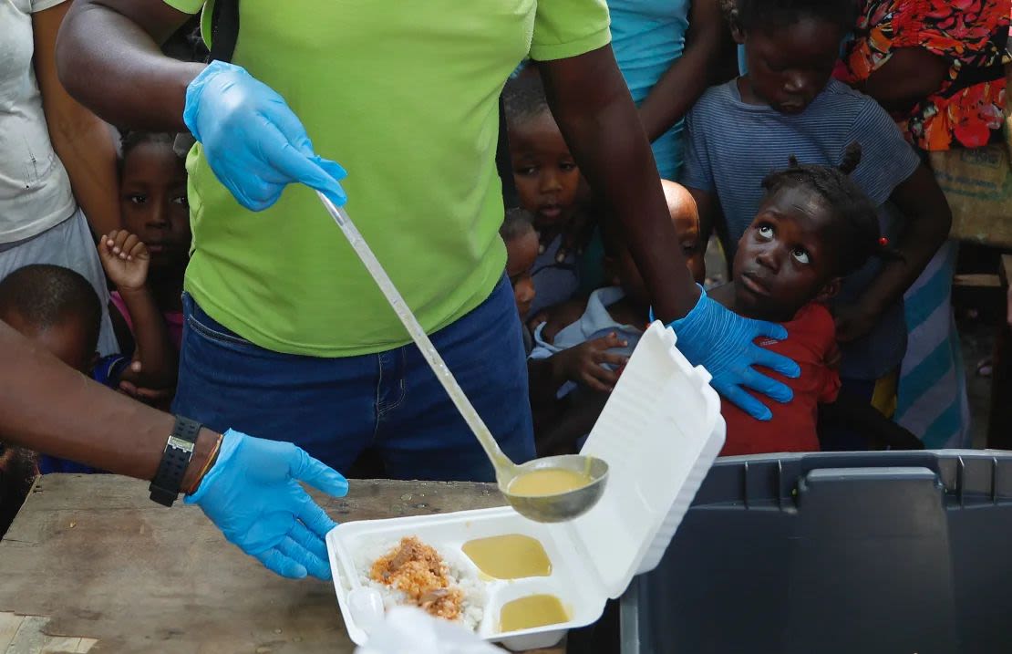 Sirven sopa en un recipiente mientras los niños hacen fila para recibir comida en un refugio para familias desplazadas por la violencia de las pandillas, en Puerto Príncipe, Haití, el jueves 14 de marzo de 2024. Odelyn Joseph/AP