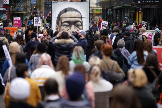 Floyd, un hombre negro de 46 años, murió bajo custodia policial en mayo de 2020. Su muerte provocó protestas generalizadas y reavivó conversaciones sobre raza, brutalidad policial e injusticia social. En esta foto la gente se arrodilla frente a un mural de Floyd durante una protesta en Manchester, Inglaterra, el 27 de marzo de 2021.