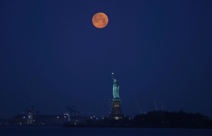 La luna se ubica detrás de la Estatua de la Libertad antes del amanecer en Nueva York. Gary Hershorn / Corbis News / Getty Images