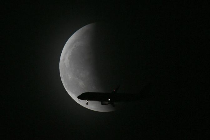 Un avión pasa frente a la luna durante el eclipse lunar en Shenyang, China. VCG / Getty Images