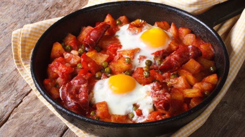 Huevos horneados al estilo vasco: una cazuela española con huevos cocidos en la mezcla se sirve con pan crujiente para mojar. Shutterstock