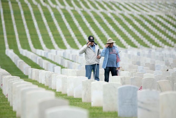 Larry Bustetter, izquierda, un veterano de la Fuerza Aérea, y Henry Knebel, un veterano del Ejército, saludan después de colocar banderas en el Cementerio Nacional de Los Ángeles el sábado. Myung J. Chun / Los Angeles Times / Getty Images