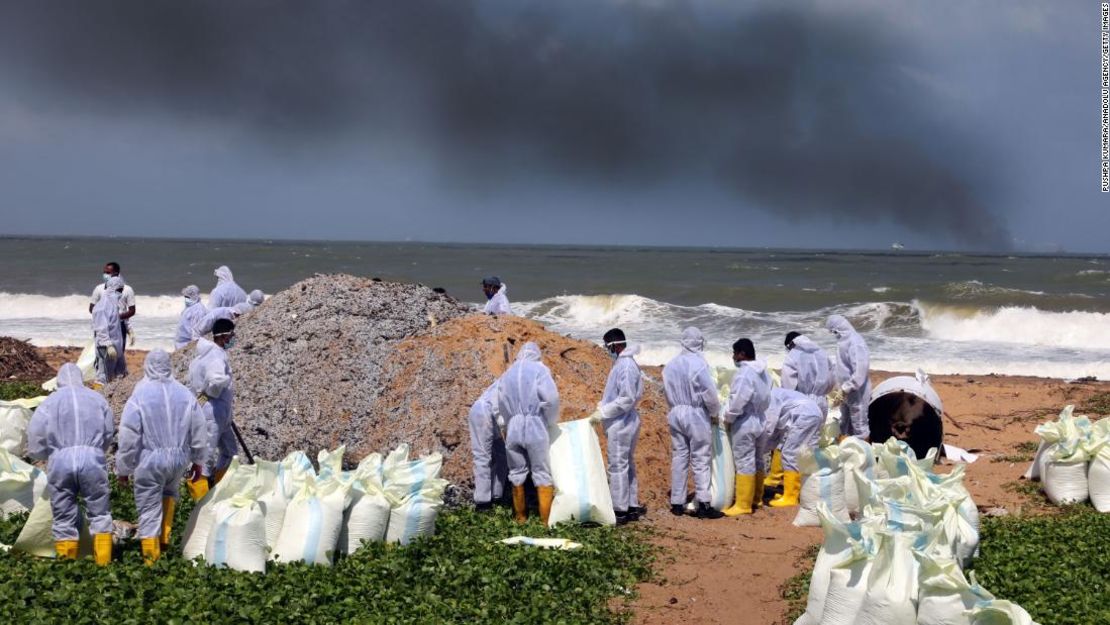 Miembros de la Marina de Sri Lanka vestidos con trajes protectores trabajan limpiando los deshechos tóxicos en las playas en los suburbios de Colombo, el 28 de mayo.