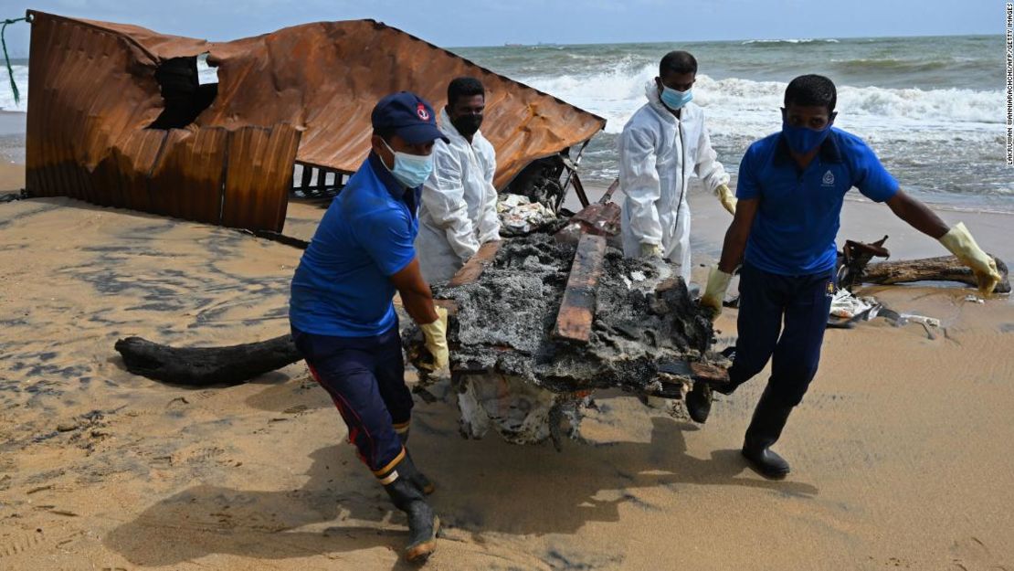 Cuatro miembros de la Marina de Sri Lanka retiran los restos de uno de los contenedores pertenecientes al buque registrado en Singapur.